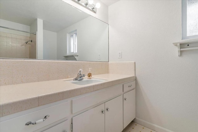 bathroom with tiled shower and vanity