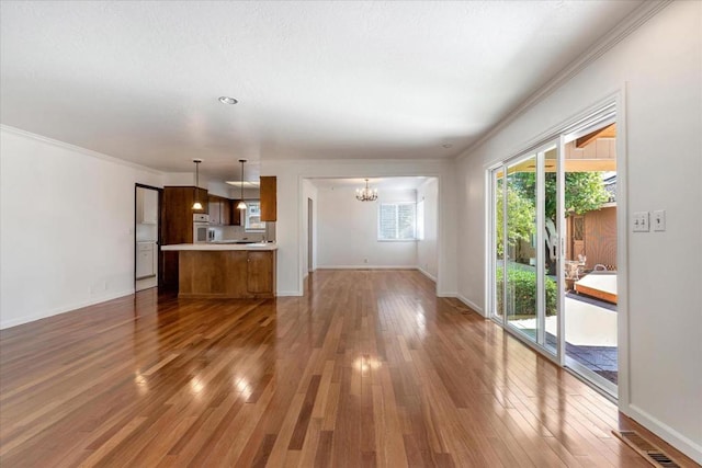 unfurnished living room featuring dark wood-type flooring, ornamental molding, and a chandelier