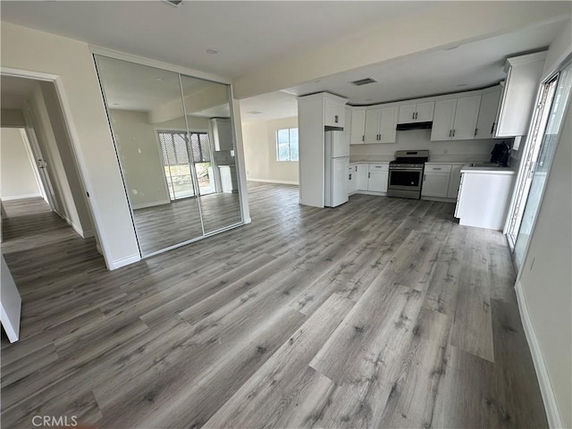 kitchen featuring white cabinetry, stainless steel range oven, white fridge, and light wood-type flooring