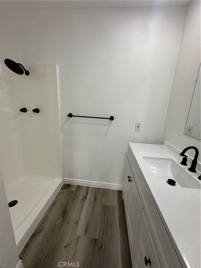 bathroom featuring walk in shower, vanity, and wood-type flooring