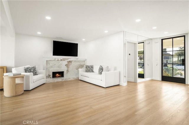 living room featuring expansive windows, light wood-type flooring, and a premium fireplace