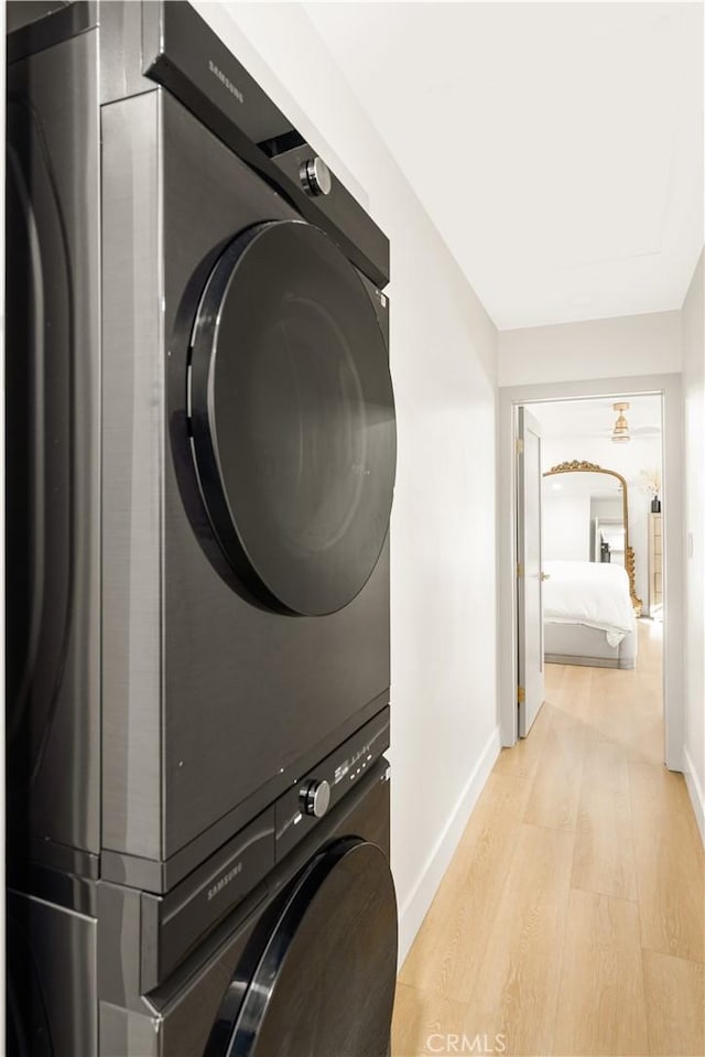 laundry area featuring stacked washer and dryer and light hardwood / wood-style flooring