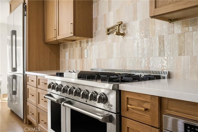 kitchen with light hardwood / wood-style floors, premium appliances, and tasteful backsplash