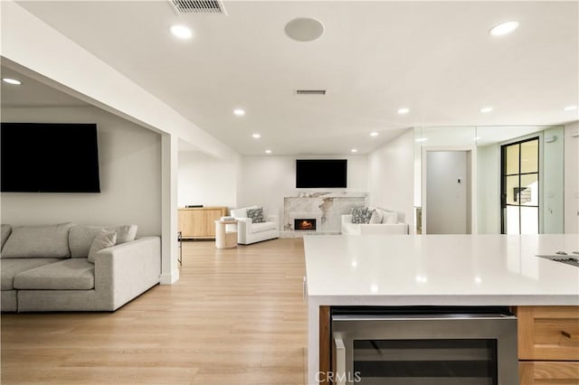 kitchen with light hardwood / wood-style floors, a high end fireplace, and wine cooler