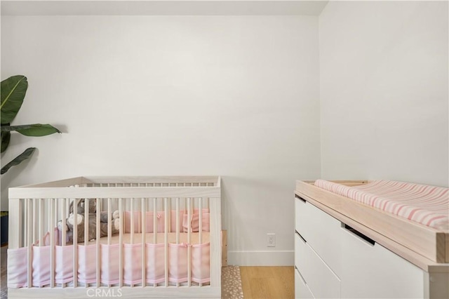 bedroom with a nursery area and light hardwood / wood-style flooring