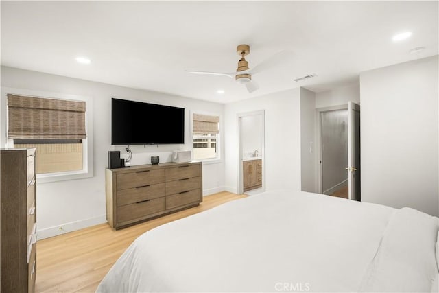 bedroom featuring ceiling fan, light hardwood / wood-style floors, and connected bathroom