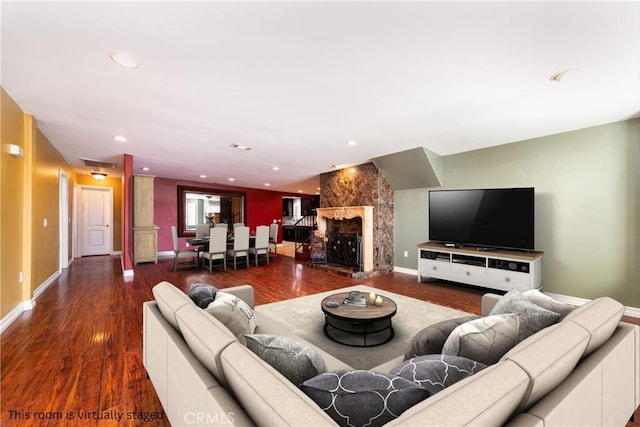 living room with dark wood-type flooring and a large fireplace