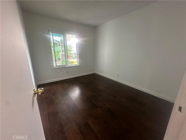 unfurnished room featuring dark hardwood / wood-style flooring and a textured ceiling