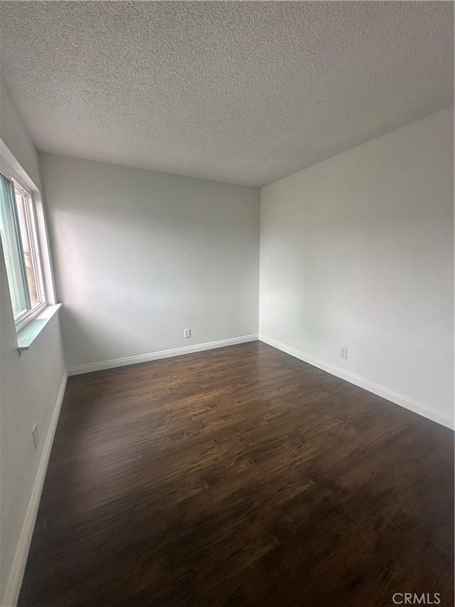 spare room featuring a textured ceiling and dark wood-type flooring