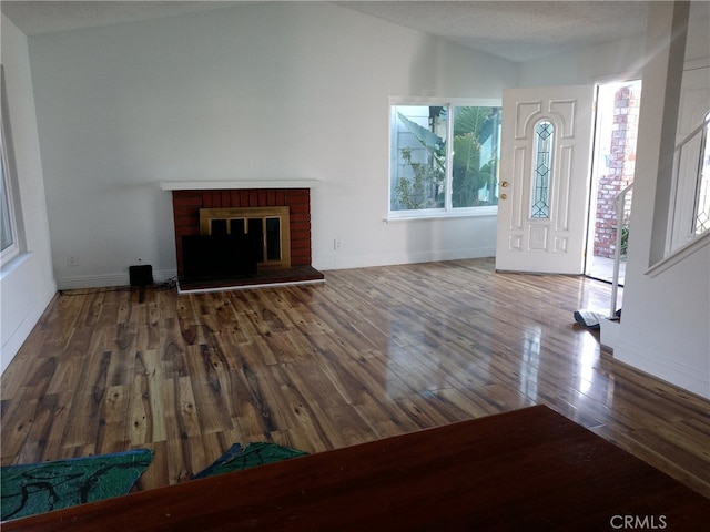 foyer entrance featuring a fireplace, hardwood / wood-style flooring, vaulted ceiling, and a wealth of natural light