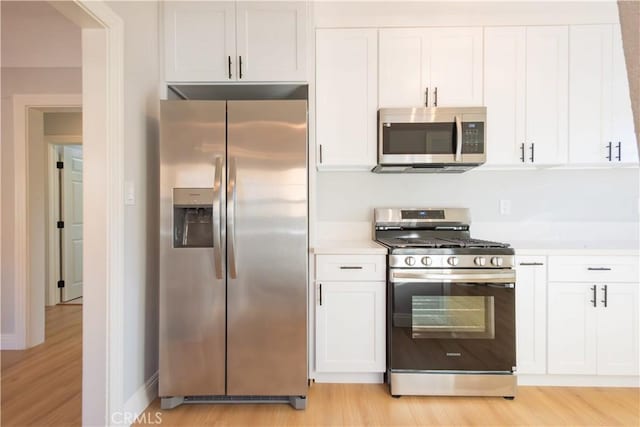 kitchen featuring stainless steel appliances, light hardwood / wood-style flooring, and white cabinetry