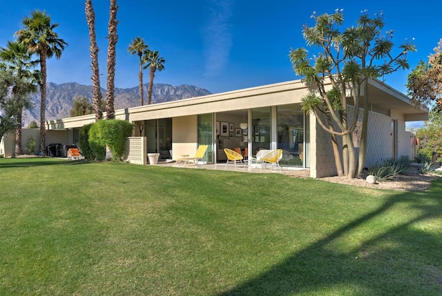 view of front facade with a mountain view, a front lawn, and a patio area