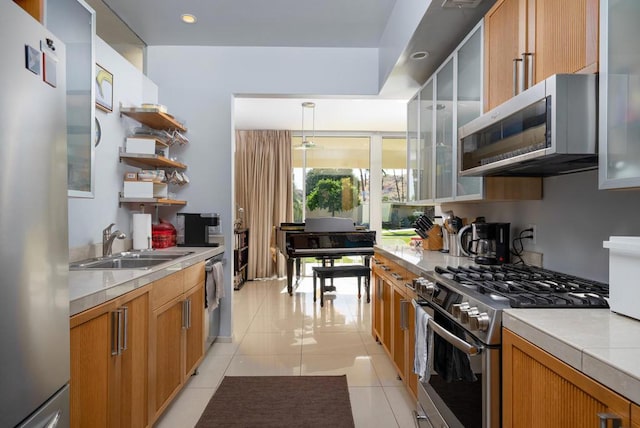 kitchen featuring decorative light fixtures, sink, light tile patterned floors, and stainless steel appliances