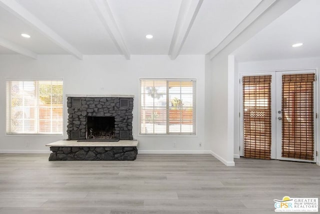 unfurnished living room with light wood-type flooring, a fireplace, and beamed ceiling