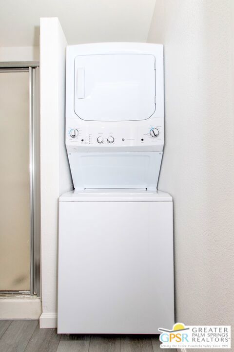 laundry room with stacked washer and dryer and hardwood / wood-style floors