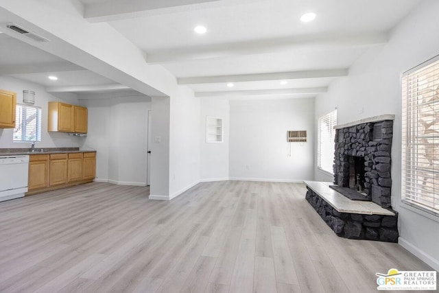 unfurnished living room with light wood-type flooring, beam ceiling, and a stone fireplace