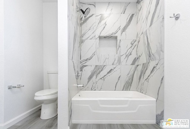 bathroom with hardwood / wood-style floors, toilet, and tiled shower / bath combo