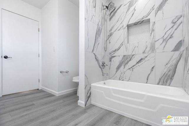 bathroom with washtub / shower combination, hardwood / wood-style floors, and toilet