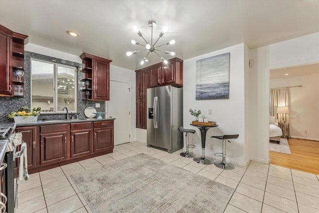 kitchen featuring tasteful backsplash, sink, light tile patterned floors, and stainless steel appliances