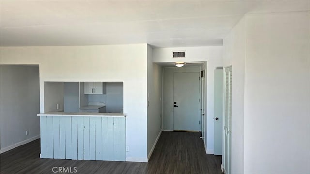 interior space with kitchen peninsula and dark wood-type flooring