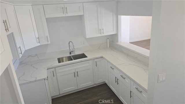 kitchen with dark hardwood / wood-style flooring, white cabinetry, sink, and light stone counters