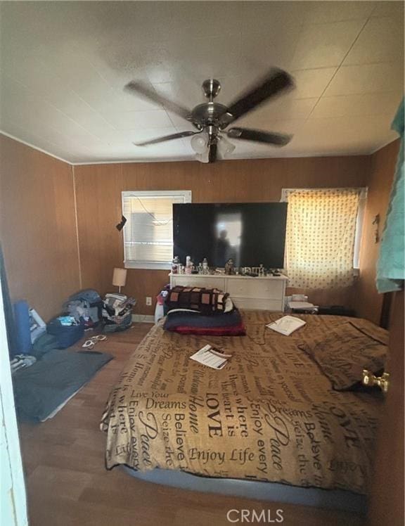 bedroom with ceiling fan, hardwood / wood-style floors, and wood walls