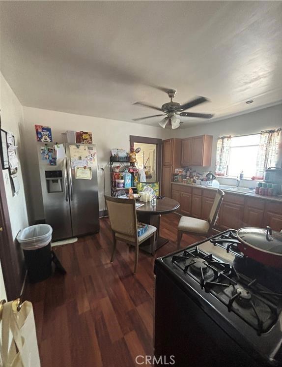 kitchen with black gas range, ceiling fan, sink, stainless steel fridge with ice dispenser, and dark hardwood / wood-style floors