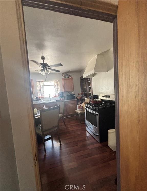 kitchen with stainless steel range, dark hardwood / wood-style flooring, ventilation hood, and ceiling fan