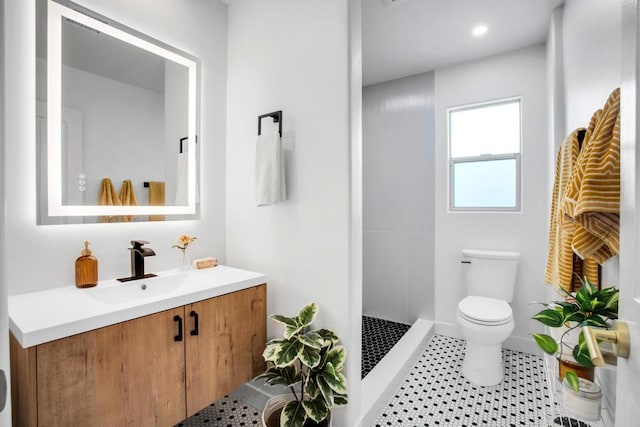 bathroom with toilet, a tile shower, vanity, and tile patterned floors