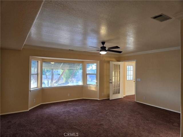 spare room with dark colored carpet, a healthy amount of sunlight, and a textured ceiling