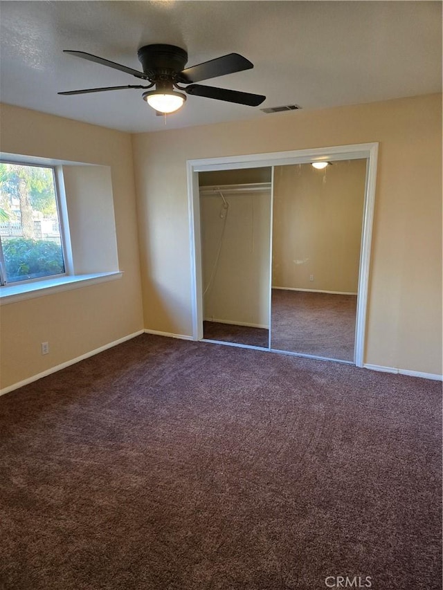 unfurnished bedroom with a closet, dark carpet, and ceiling fan