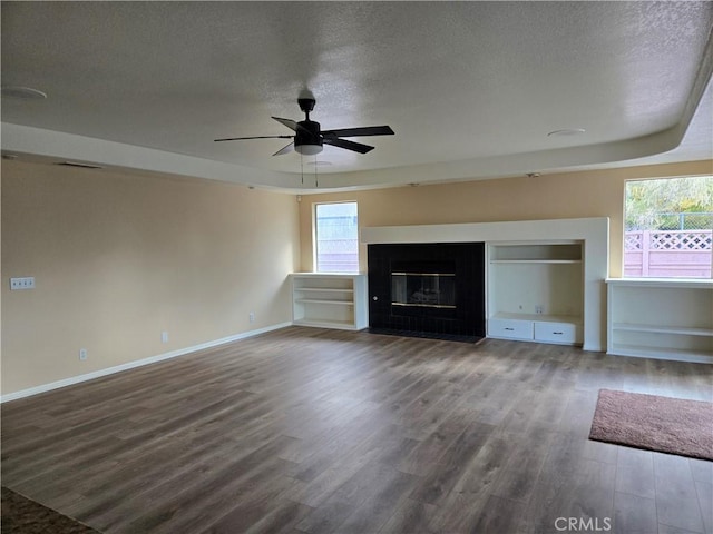 19345 Oneida Rd, Apple Valley, CA 92307 - unfurnished living room with wood finished floors, a ceiling fan, a textured ceiling, healthy amount of natural light, and a glass covered fireplace