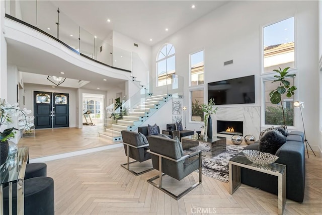 living room featuring a wealth of natural light, light parquet flooring, and a towering ceiling