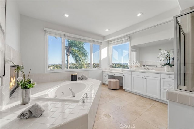 bathroom featuring tile patterned flooring, vanity, and tiled bath