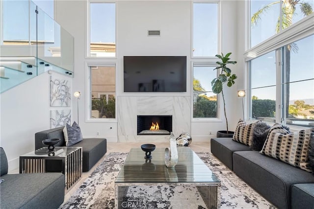 living room featuring a premium fireplace, plenty of natural light, and a high ceiling