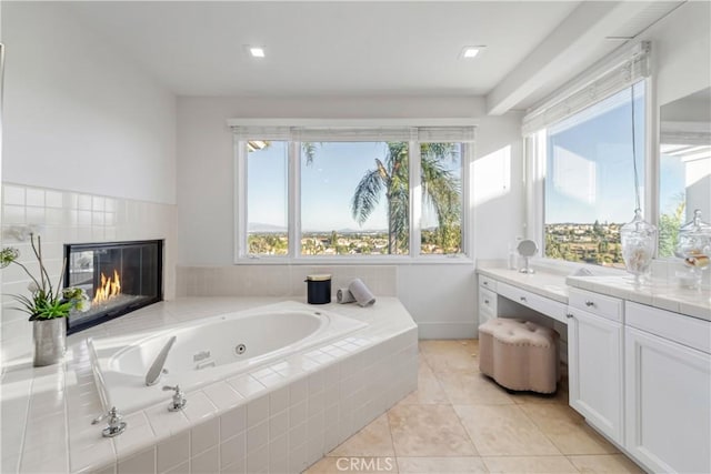 bathroom with a relaxing tiled tub, vanity, and a healthy amount of sunlight