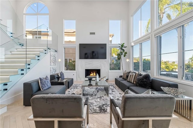 living room with a fireplace, a high ceiling, and light wood-type flooring