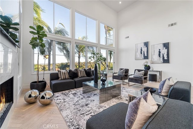 living room featuring plenty of natural light, a towering ceiling, and parquet flooring