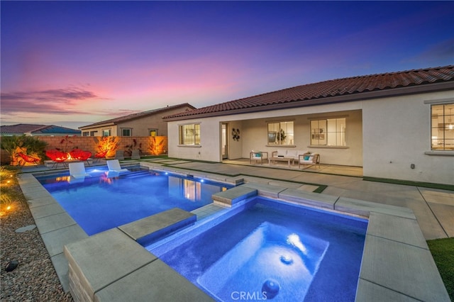 pool at dusk featuring an in ground hot tub and a patio area