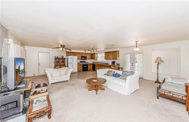 living room featuring ceiling fan, french doors, light colored carpet, and sink