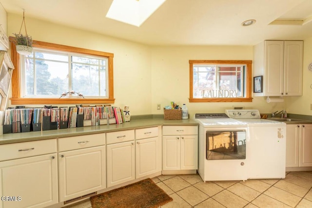 washroom with a skylight, sink, cabinets, separate washer and dryer, and light tile patterned flooring