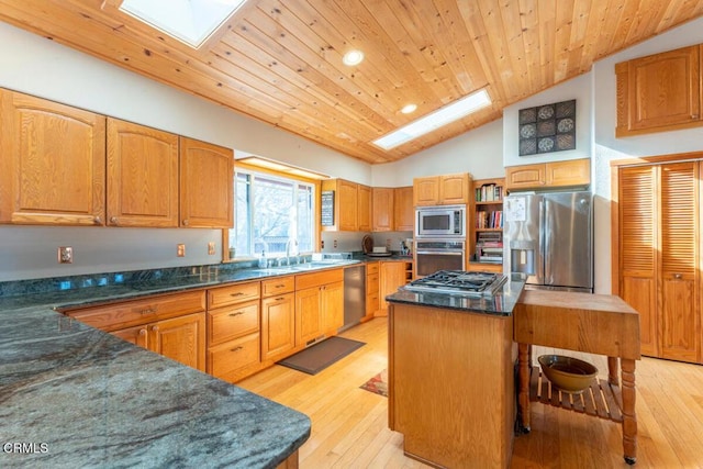 kitchen with vaulted ceiling with skylight, a center island, light hardwood / wood-style flooring, and appliances with stainless steel finishes