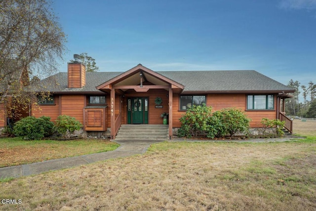 view of front of home featuring roof with shingles, a chimney, and a front lawn