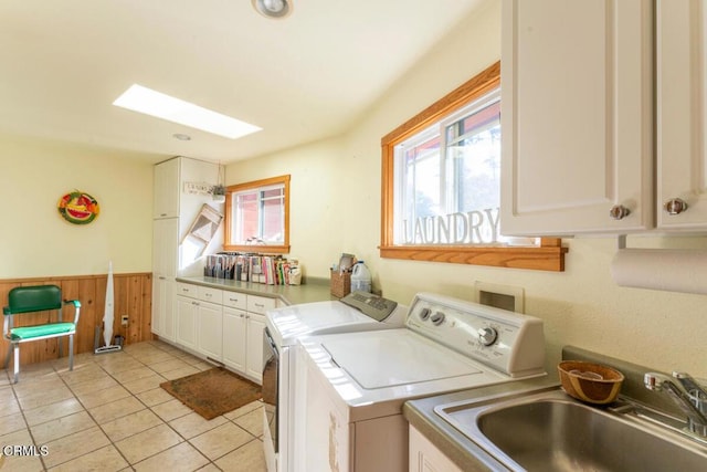 laundry room with light tile patterned floors, washing machine and dryer, wainscoting, cabinet space, and a sink