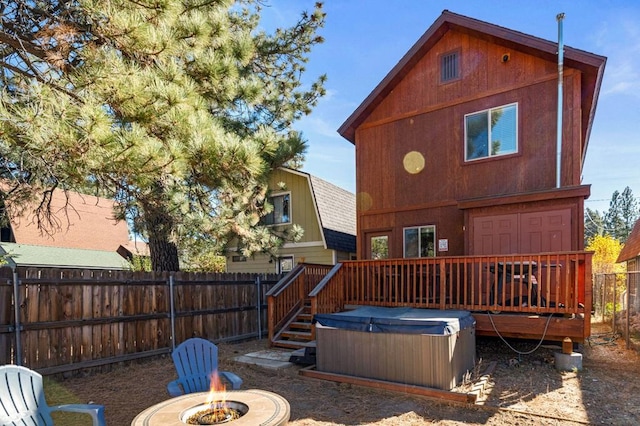 rear view of house with an outdoor fire pit, a wooden deck, and a hot tub