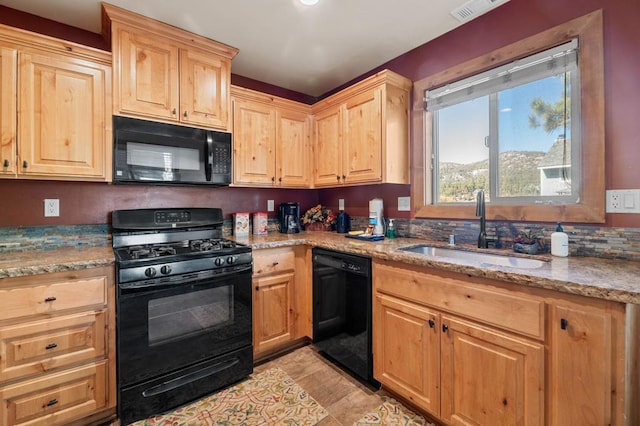 kitchen with light stone countertops, light tile patterned floors, sink, and black appliances