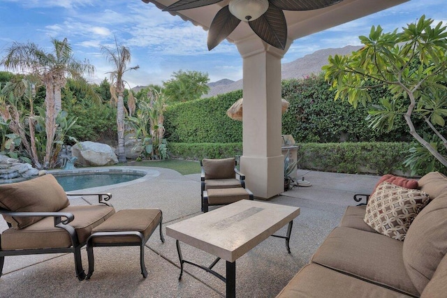 view of patio featuring a mountain view, ceiling fan, and a fenced in pool