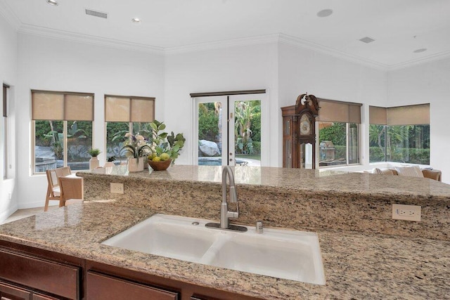 kitchen with light stone counters, crown molding, and sink