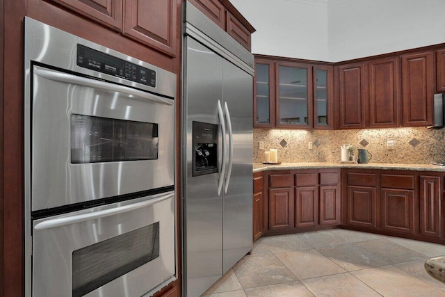 kitchen featuring light stone counters, light tile patterned floors, backsplash, and appliances with stainless steel finishes