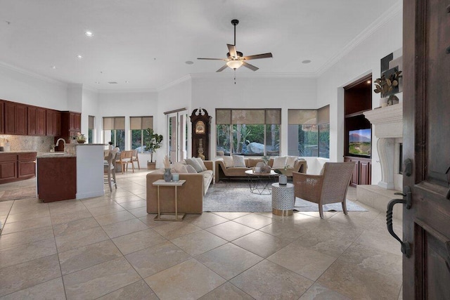 living room featuring a towering ceiling, ceiling fan, crown molding, and sink